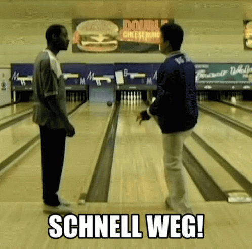 two young men standing in a bowling alley on a bowling ball