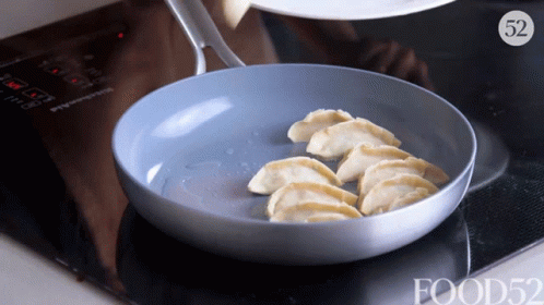 a pan on top of an oven cooking dumplings