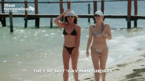 two girls standing in the ocean in bikinis