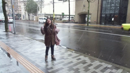 woman with umbrella standing in the rain on the side walk