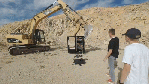 two men stand near a small excavator on an alien like hill