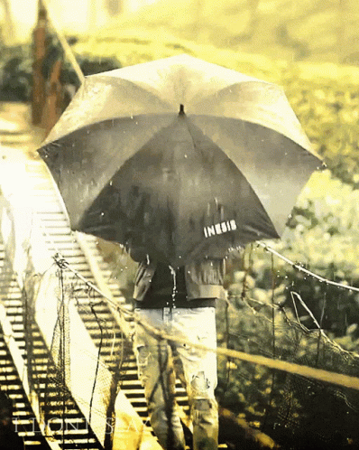 people in the rain under an umbrella on the train tracks