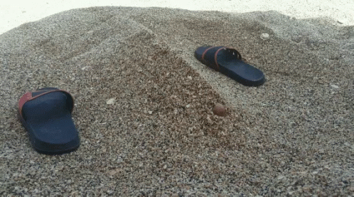 a pair of shoes on the sand and one on top