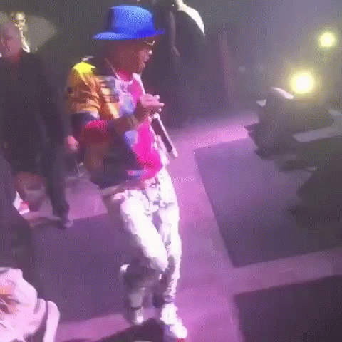 man walking into a dark room with bright colors and a colorful hat on