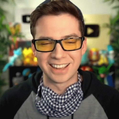 a smiling man in blue glasses looks up