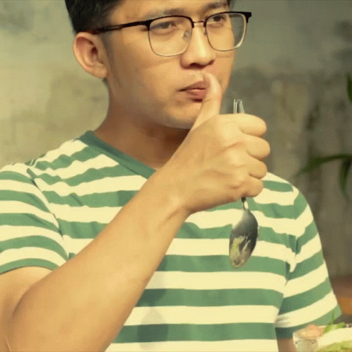 a young man holds up a spoon with toothpaste