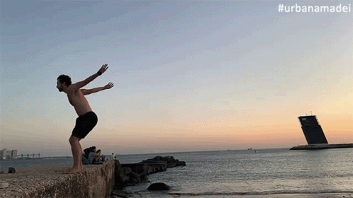 a man on a ledge of rocks throwing a frisbee