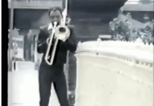 man in suit holding trumpet on the sidewalk
