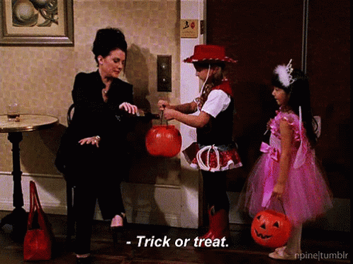 a man sits in the corner with two girls and a trick or treat sign on