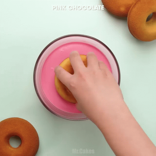 the blue donuts are near a hand and a doughnut