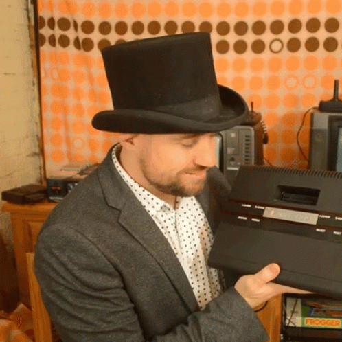 a man in a top hat looking at an old fashioned radio