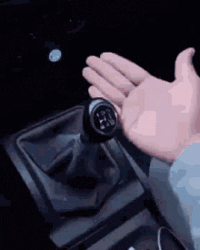 hand in white glove holding remote control in dark room