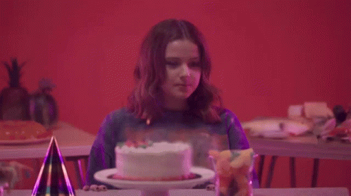 a woman looks down as she blows out her birthday cake