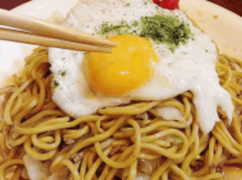 noodles on plate being eaten with chopsticks and a bottle