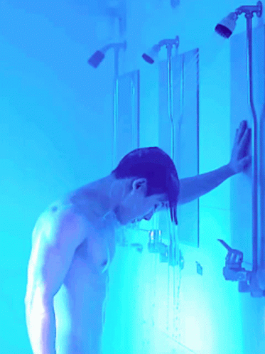 a  man with an open showerhead in a yellow room