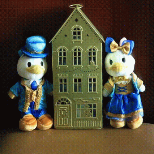 two stuffed animals sit by a doll house