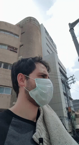 a man wears a protective mask as he stands in front of a building
