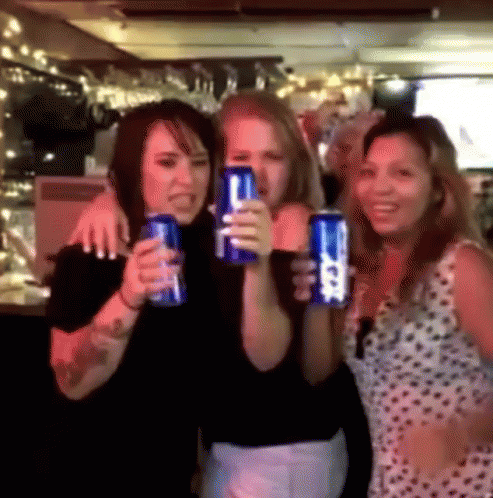 three women holding up some drinks and smiling