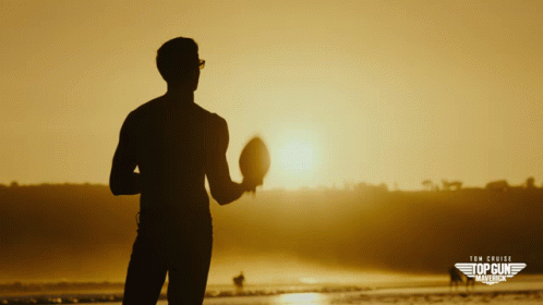 a silhouette of man holding a baseball ball with the sun shining behind him