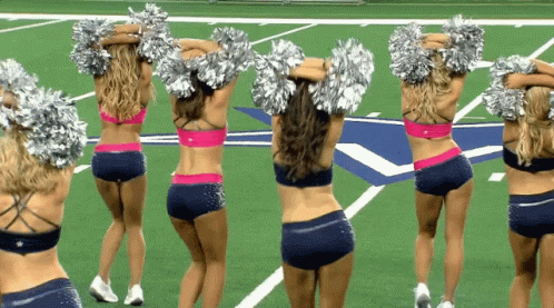 several women in cheerleaders with silver hair standing on a football field