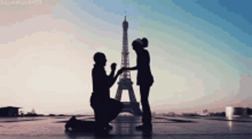 two people standing next to each other in front of the eiffel tower