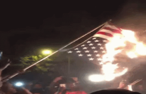 a person holding a flag in front of fireworks