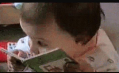 young child using video camera and reading a book
