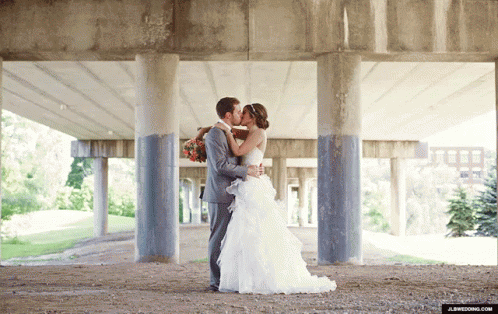 a bride and groom are kissing under a building
