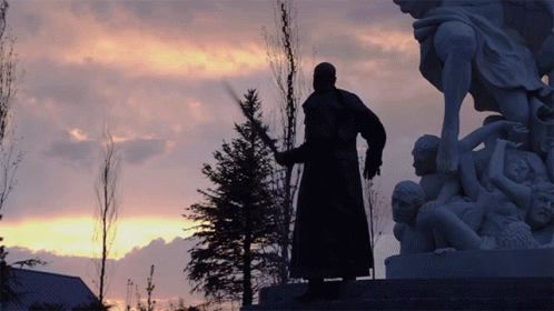 a man is in front of a statue at dusk