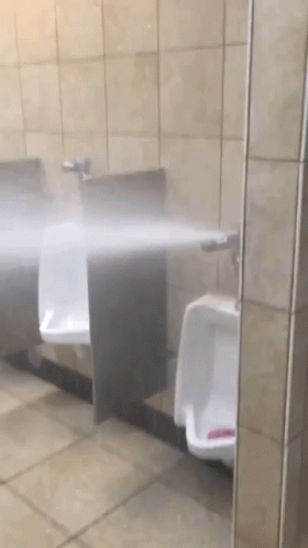 a restroom with three urinals that have the water spray in front