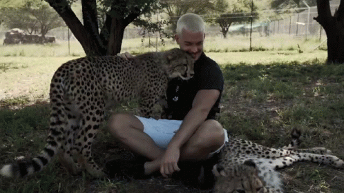 a man with his arm around an adult cheetah