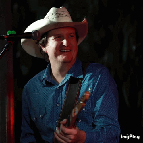 a man in a cowboy hat playing a guitar