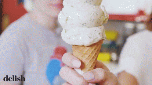 a person wearing white with paint on them holds an ice cream cone