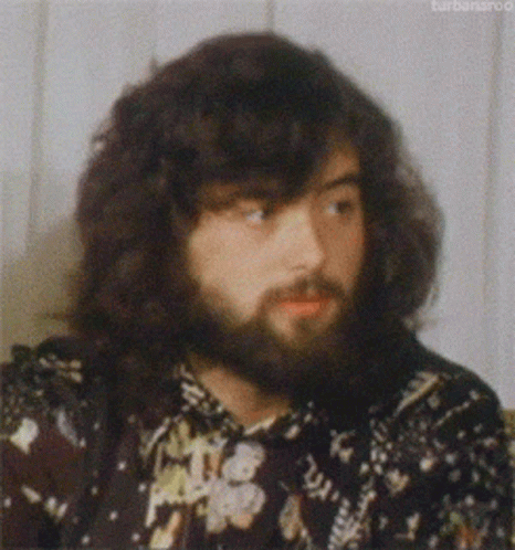 a man with long curly hair is wearing a flowered shirt