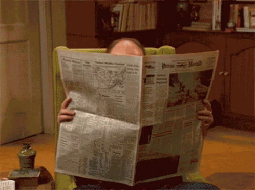 a person holding onto a newspaper and reading it