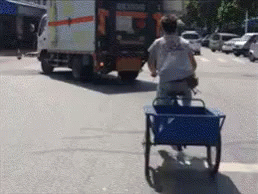 a man rides his bicycle on the street with carts