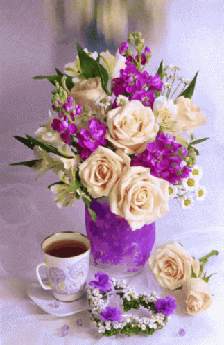 a pink and blue vase with some flowers next to a cup