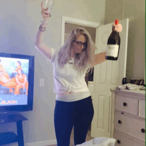a woman standing in front of a tv holding a wine bottle