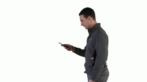 a man holding a cell phone standing up against a wall