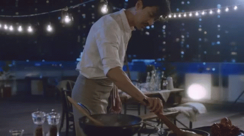 a male in a white shirt preparing food in a frying pan