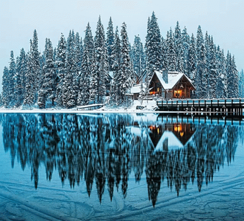 a snow covered mountain with a house and lake in front