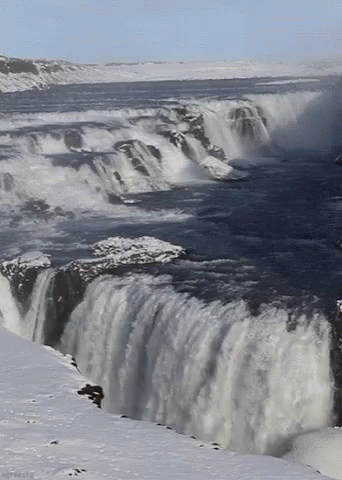 a person skiing over the edge of a very tall waterfall