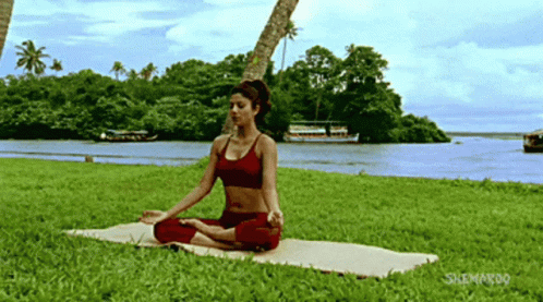a woman in a sports  top is practicing yoga on the beach