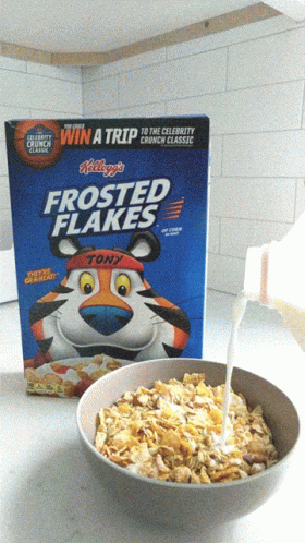 a bowl with blue frosted flakes next to a box of frosted flakes