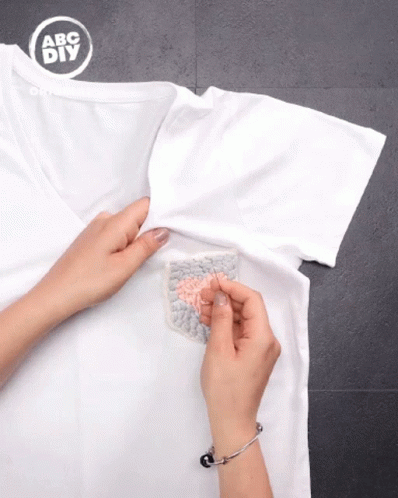 a hand uses a glove to clean a t - shirt