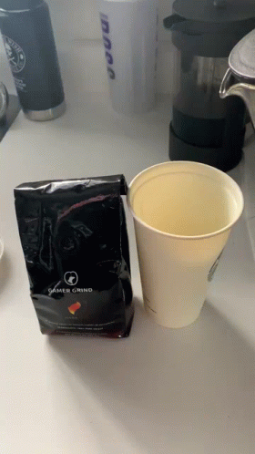 coffee in a cup is next to a black bag