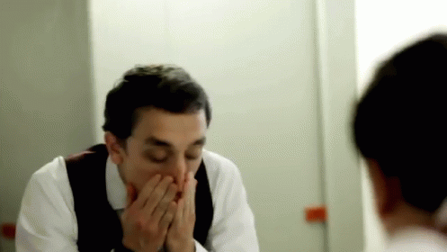 a man wiping his nose in front of a mirror