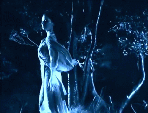 a woman is standing near a tree in the dark