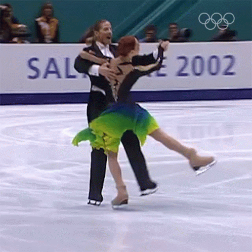 two people in figure skating attire hugging