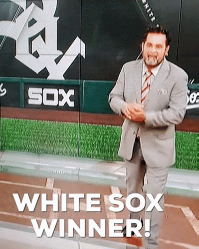 man in business suit standing in front of an advertit for a sox baseball team